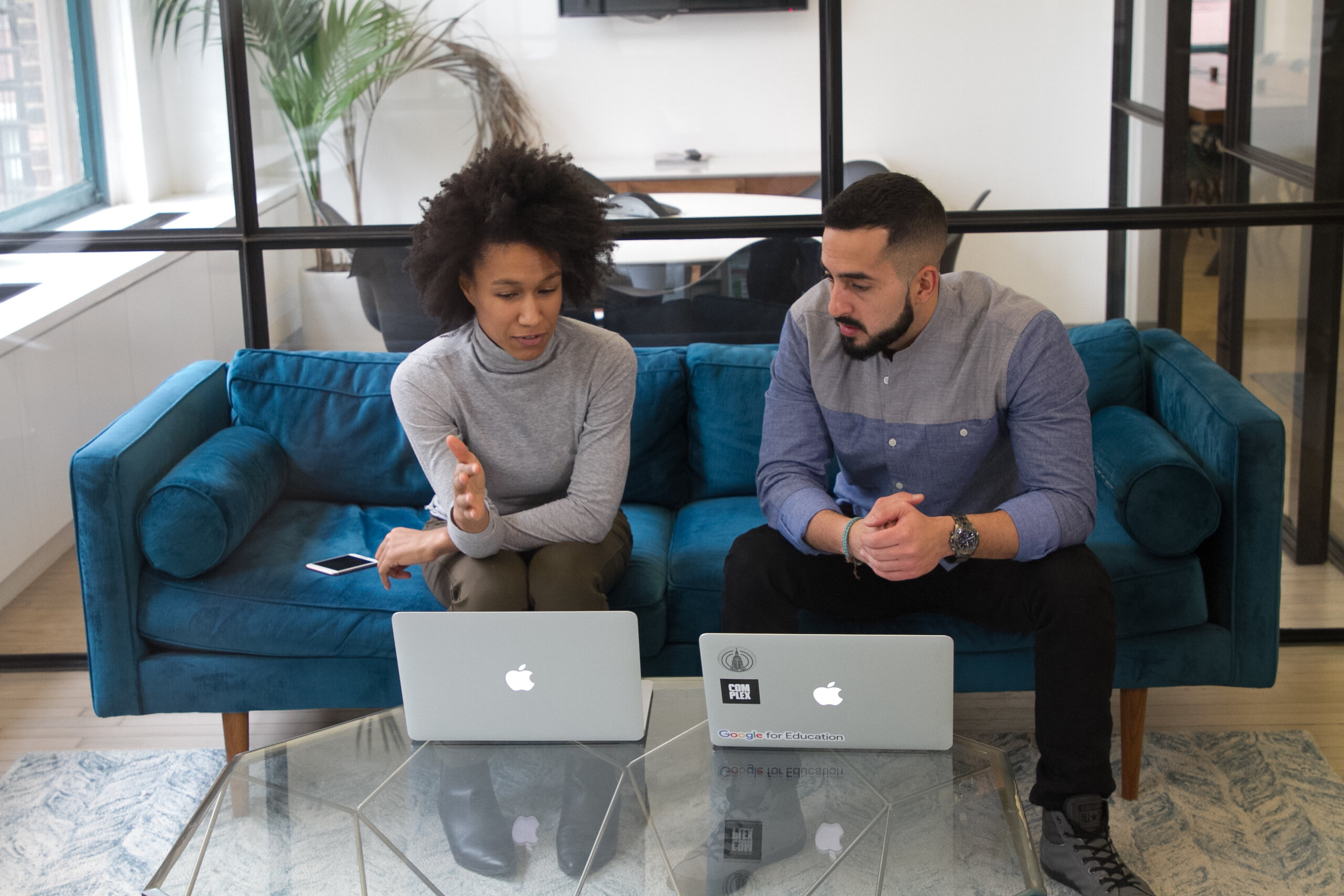 Woman and man sitting on couch looking at laptops